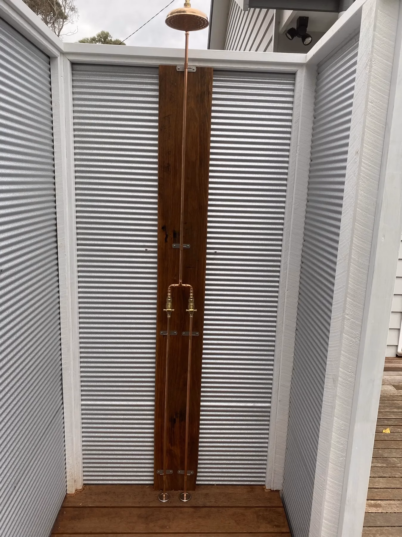 Outdoor shower and copper pipework against a timber mounting panel